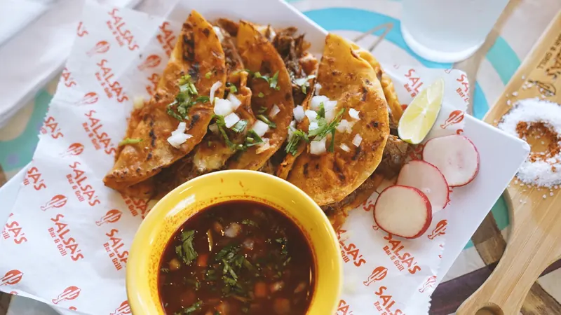 Tacos de Birria with consomé for dipping, radishes and lime